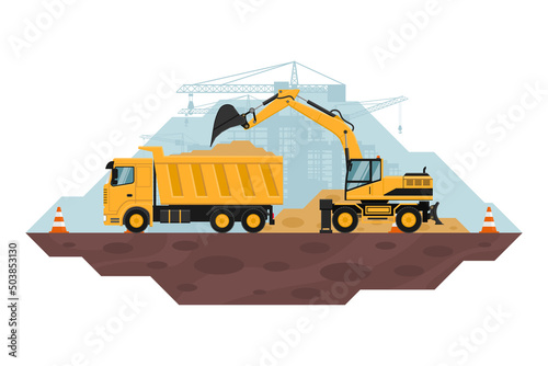 Wheel excavator filling a dump truck, heavy machinery used in the construction and mining industry. safety cones