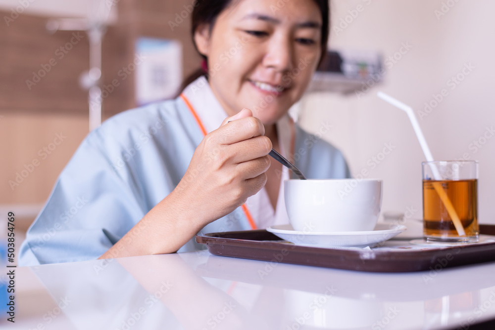 Sick asian woman patient eating meal on sickbed in the hospital Sick asian woman patient eating meal on sickbed in the hospital