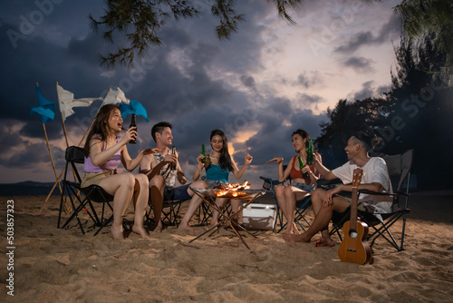 Group of Asian young man and woman having party on the beach at night. 