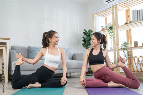 Asian active woman friend doing Yoga Pilates workout together at home. 