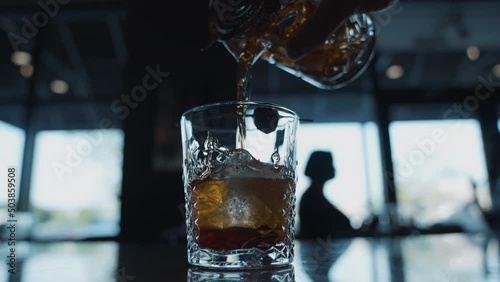 Pouring cocktail into glass on a bar