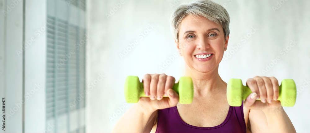 Sporty mature woman training with dumbbells at home Sporty mature woman training with dumbbells at home