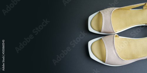 women's shoes of beige color on a black background. the shoes are removed from the top. Banner for insertion into site. Horizontal image.