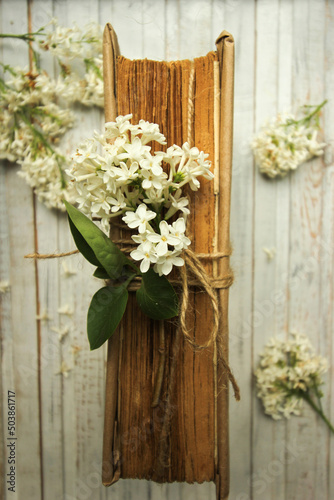 Spring romantic composition with white lilac flowers and old book on wight wooden background
