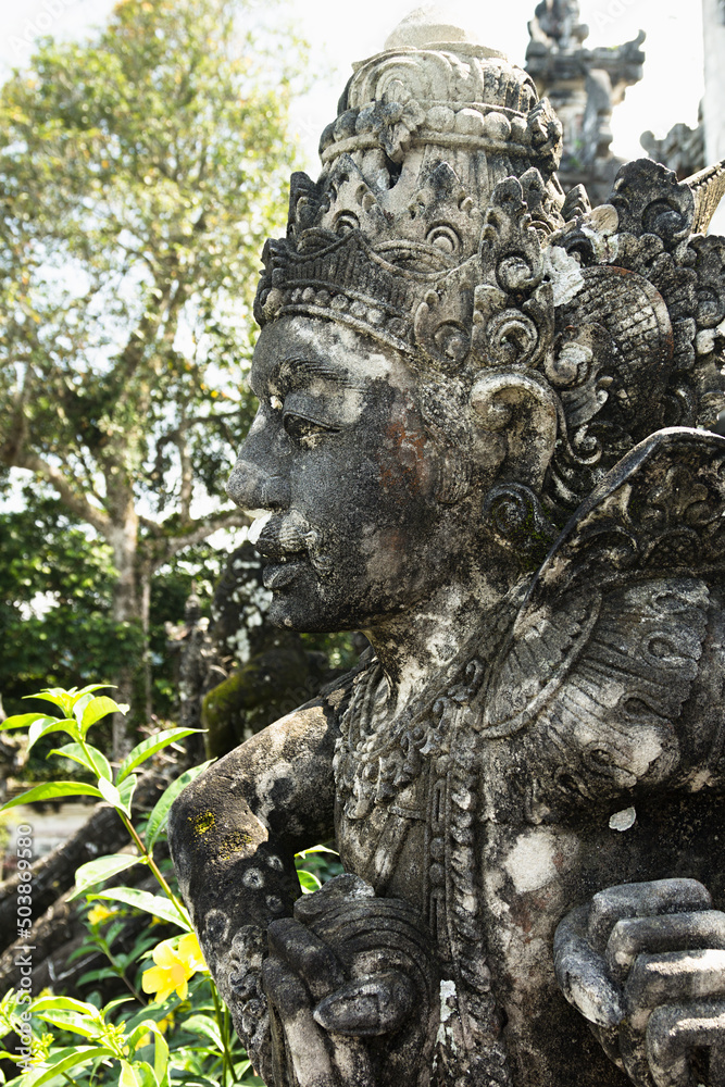 Sacred sculpture of human deity carved of stone decorate of traditional balinese sacred temple Lempuyang on Bali, vertical, fragment. Majestic landmarks of indonesian culture and religion.