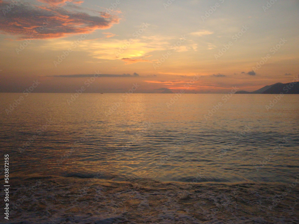 Calm sea at dawn. Small waves roll on the sandy beach.