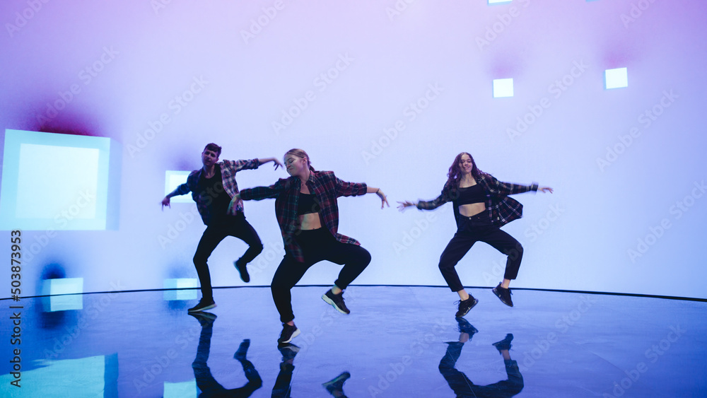 Diverse Group of Three Professional Dancers Performing a Hip Hop Dance Routine in Front of a Big Led Wall Screen with VFX Animation During a Virtual Production in Studio Environment. 105 BPM Song.