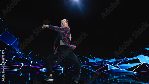 Stylish Young Professional Female Dancer Performing a Hip Hop Dance Routine in Front of Big Led Wall Screen with VFX Animation During a Virtual Production in Studio Environment. 105 BPM Song.