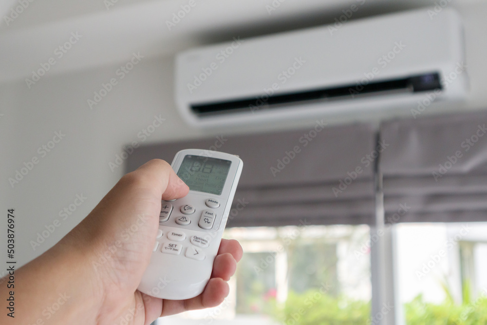 Hand with remote control directed on air conditioner