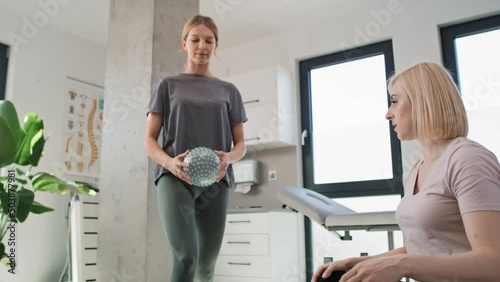 Female physical therapist working with young woman using exercising ball. Shot with RED helium camera in 8K.   photo