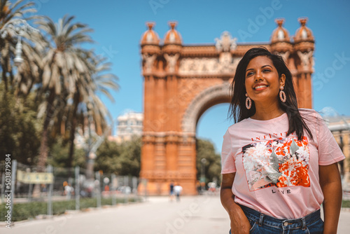 Photography Young smiling Hispanic female in Barcelona with the Arc de Triomf on the backgro