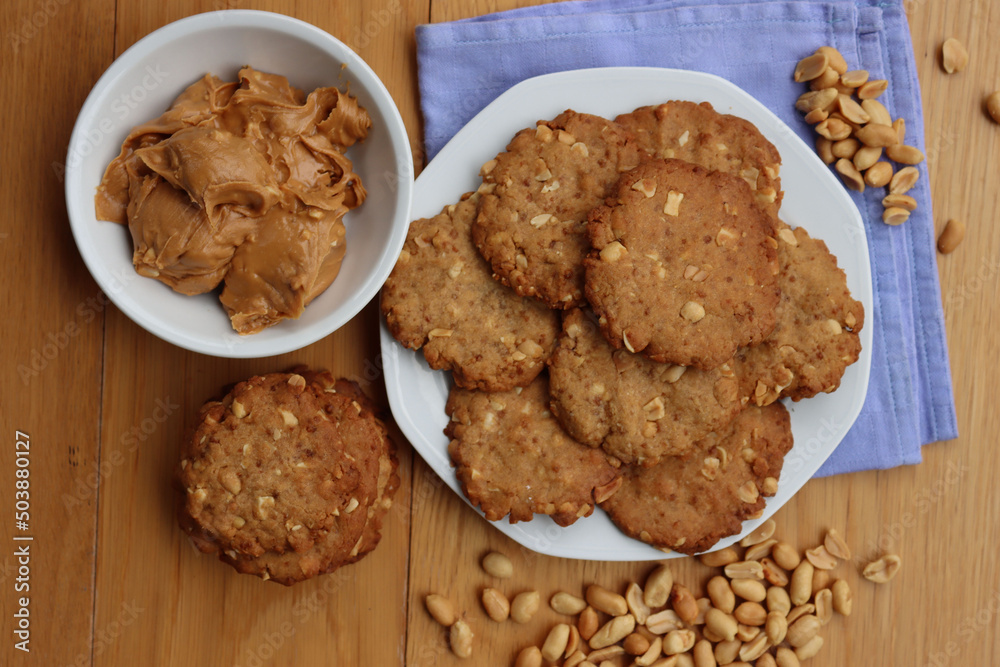 Peanut butter cookies on a plate with peanuts and peanut butter cream on wooden table Traditional american dessert Peanut butter cookies on a plate with peanuts and peanut butter cream on wooden table Traditional american dessert