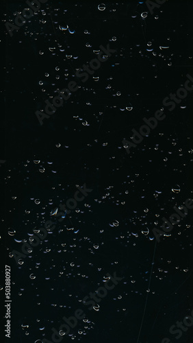 Water drop texture. Wet glass overlay. Night rain dew. Weathered surface. Transparent liquid bubbles scratch on dark black window abstract background.