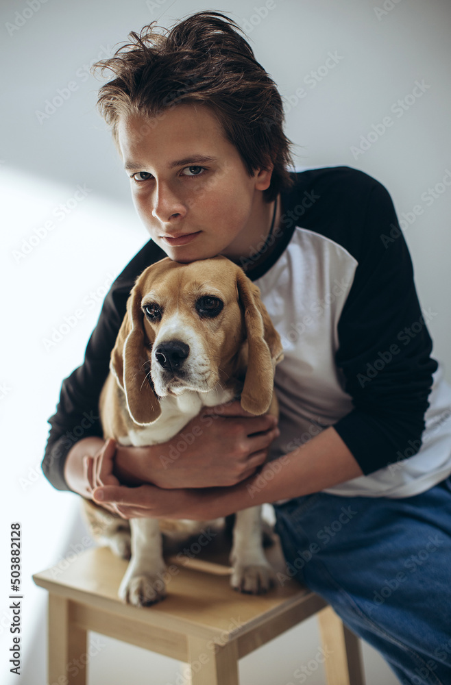 Portrait of a handsome teenage boy with a dog posing on a white background. Studio shot.Child with a dog. High quality photo