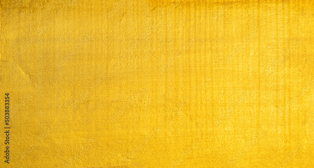 Fototapeta premium Gold wall texture background. Yellow shiny gold foil paint on wall surface with light reflection