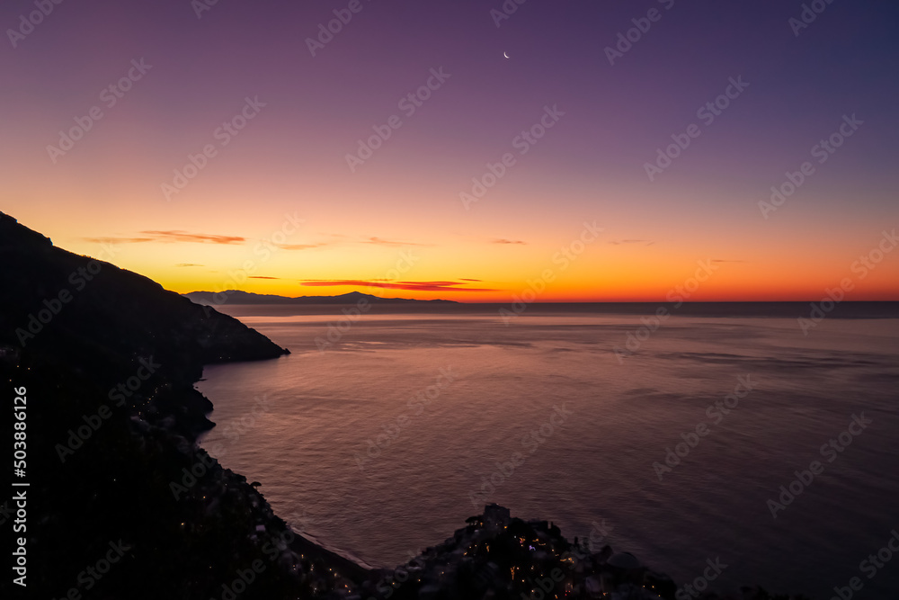 Panoramic sunrise view from hiking trail Path of the Gods between Positano and Praiano at Amalfi Coast, Campania, Italy, Europe. Calm water surface reflecting sun ray at Tyrrhenian Mediterranean Sea Panoramic sunrise view from hiking trail Path of the Gods between Positano and Praiano at Amalfi Coast, Campania, Italy, Europe. Calm water surface reflecting sun ray at Tyrrhenian Mediterranean Sea