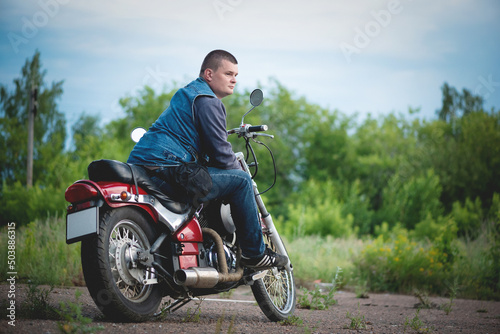 Motorcyclist is sitting on the motorbike outdoors.