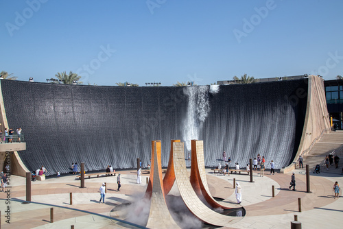 artificial waterfall with water running and people standing in the water