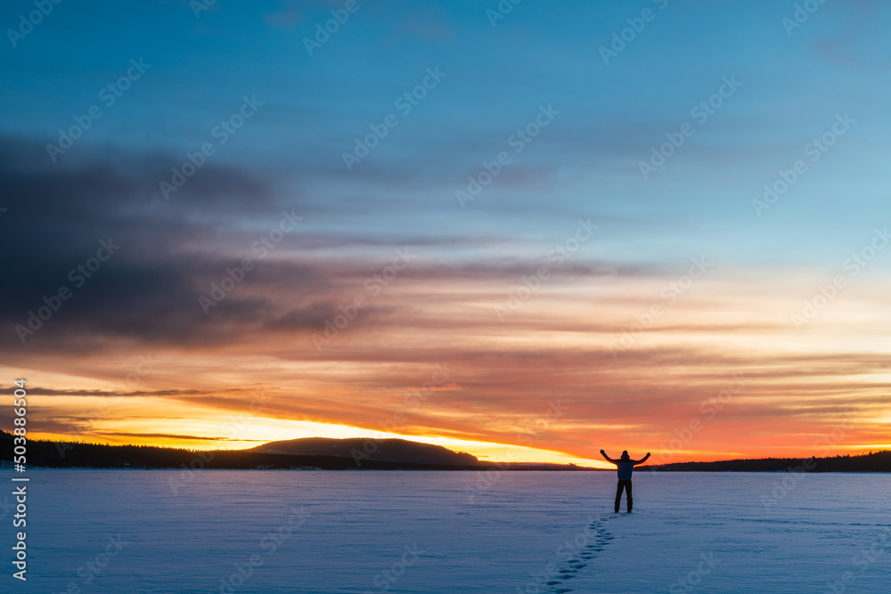 Man standing on frozen lake at sunrise