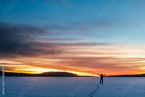 Man standing on frozen lake at sunrise