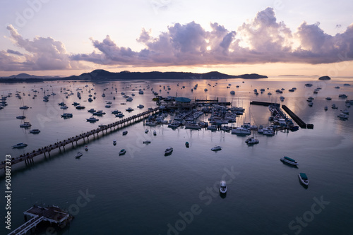 Aerial View Top down Drone shot of Yacht and sailboat parking in marina at Chalong bay Transportation and travel background concept.Beautiful sea with mountain sunrise sky clouds sunset background