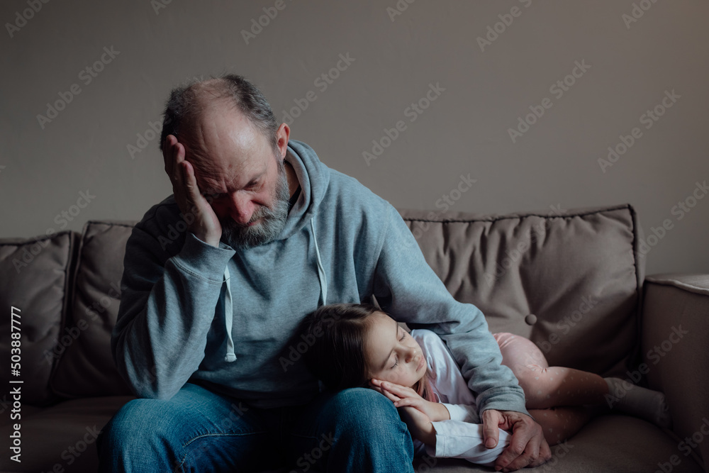 Worried middle aged hoary man supporting little frightened grandgirl. Concept of stress and fear