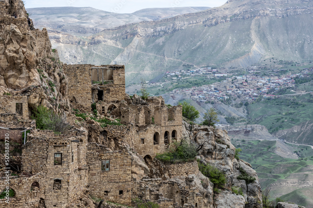 the ruins of an ancient alpine settlement in the mountains of Dagestan against the backdrop of mountains and blue sky