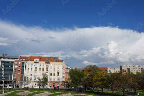 Square with houses and trees, blue sky and white cloud