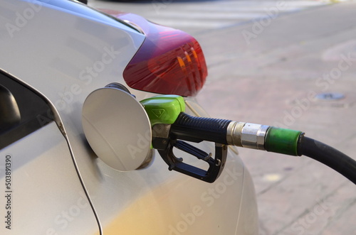 Refueling modern car with petrol pump on gas station, closeup. White car refueling at gas station with green fuel nozzle. refueling gun in the tank  photo