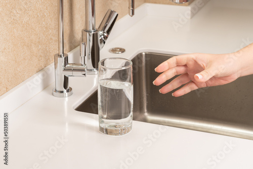 girl picking up a glass of drinking water in the kitchen