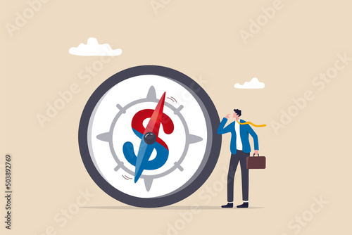 Economic direction or investment trend, financial indicator, inflation or interest rate direction, recession or growth concept, businessman investor looking at compass with dollar sign direction.