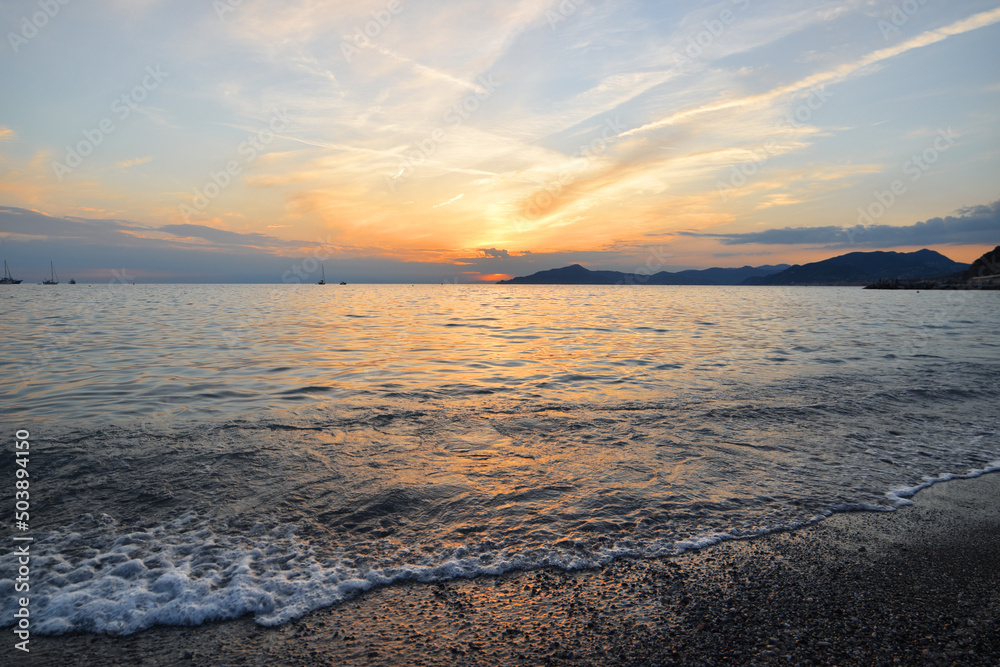 incredible colors and lights, a romantic sunset on the beach facing the sea in the magnificent Liguria