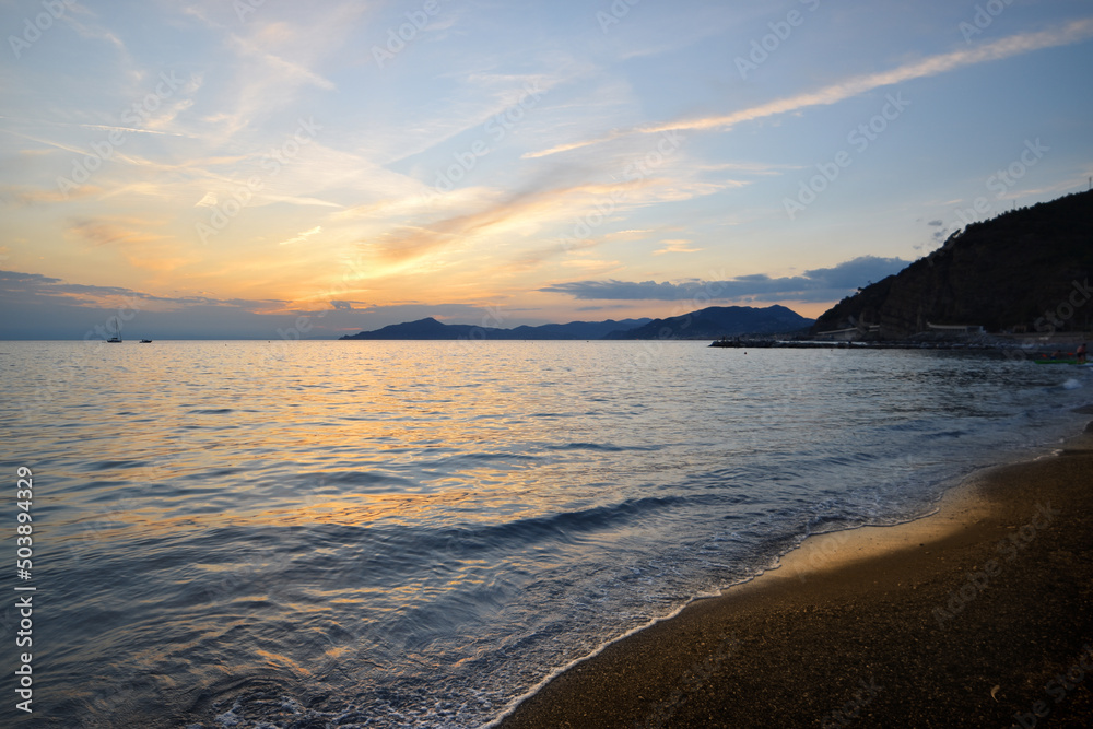 incredible colors and lights, a romantic sunset on the beach facing the sea in the magnificent Liguria