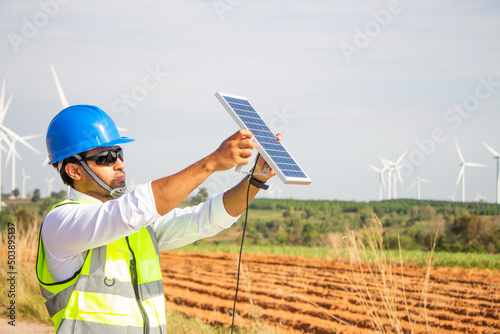 engineer team working in wind turbine farm and solar cell. Renewable energy with wind generator by alternative energy concept. 