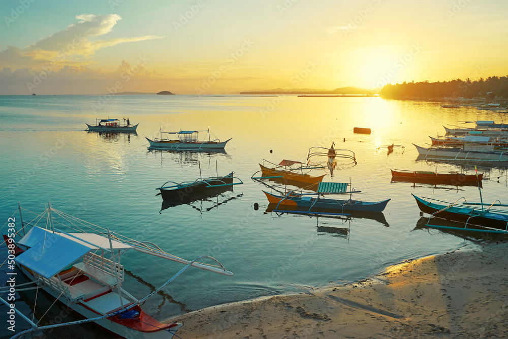 Beautiful colorful sunset on the seashore with fishing boats. Philippines, Siargao Island.