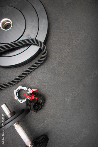 Fitness equipment on the floor at the gym. Vertical flat lay with bodybuilding equipment on a black background and empty space for text. Weight training concept