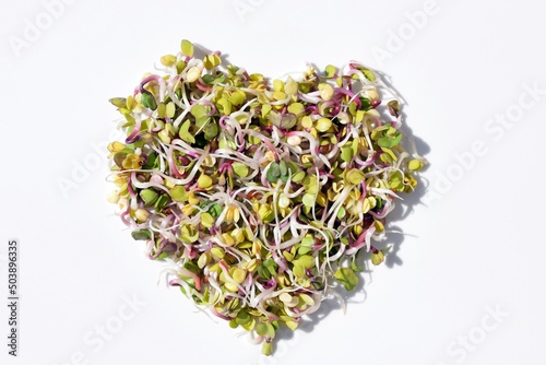 Fresh radish sprouts in a shape of heart, white background. Healthy eating concept