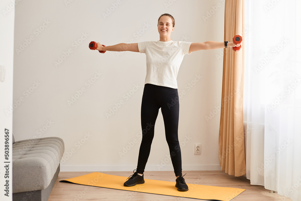 Full length portrait of of beautiful young woman doing exercises with dumbbells, athletic woman with perfect body training biceps and triceps. Strength and motivation Full length portrait of of beautiful young woman doing exercises with dumbbells, athletic woman with perfect body training biceps and triceps. Strength and motivation