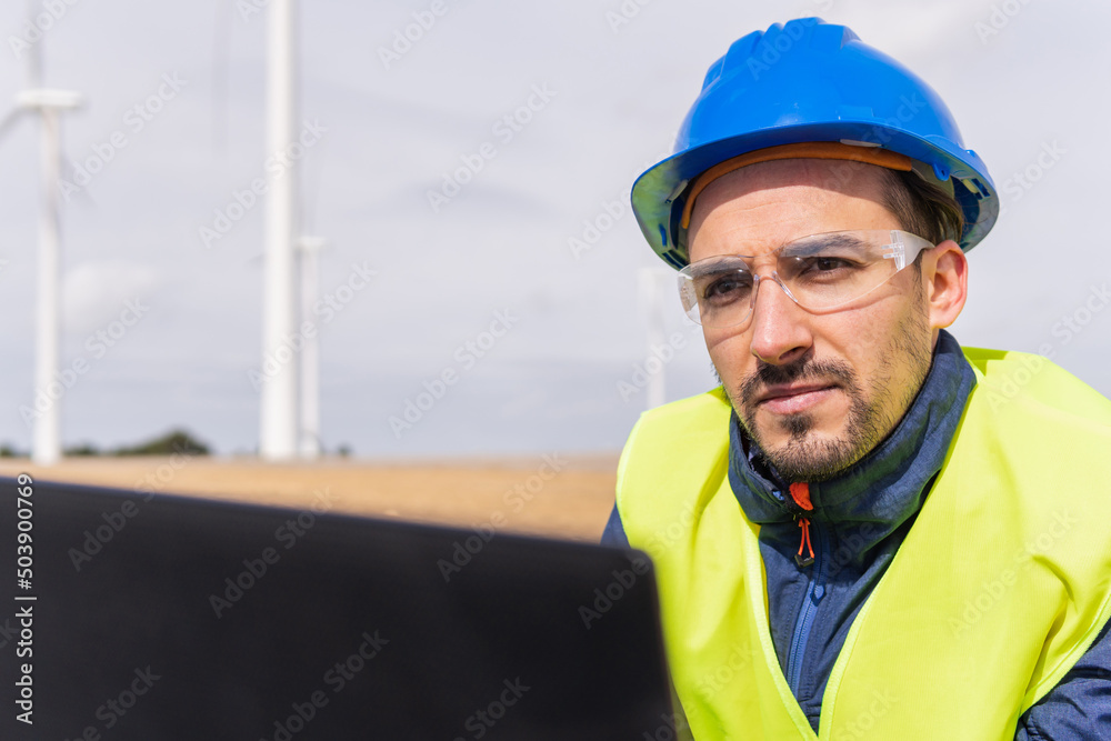 Male engineer using laptop on wind farm Male engineer using laptop on wind farm