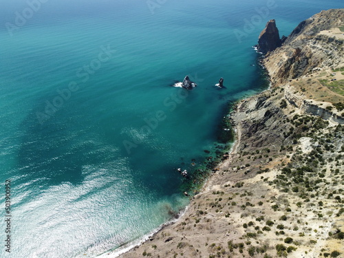 Aerial view on calm azure sea and volcanic rocky shores. Small waves on water surface in motion blur. Nature summer ocean sea beach background. Nobody. Holiday, vacation and travel concept