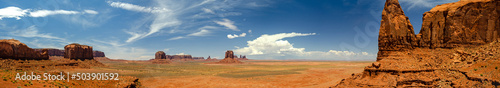 Ultra-widescreen high-res panorama of red desert with typical mesas in Monument Valley