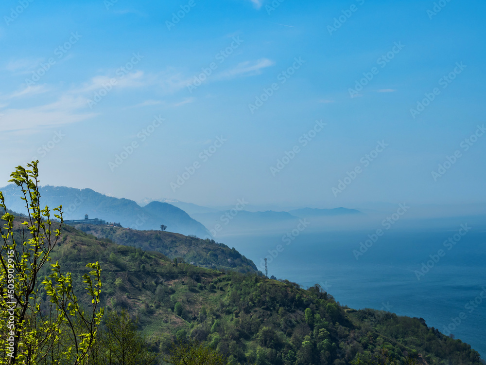 View from the observation deck to the sea and mountains. The mountains are shrouded in clouds and mist. Morning dawn in the mountains. Mountain landscape. Skyline. Blue sky. copy space