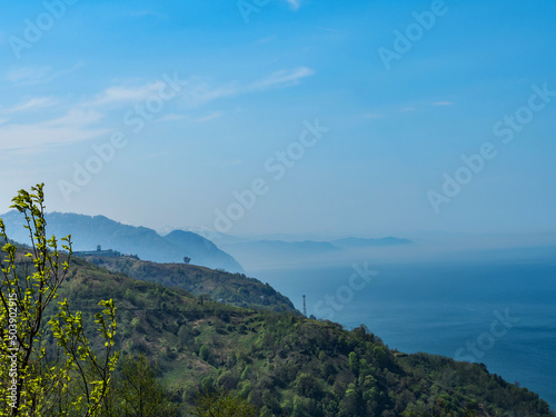 View from the observation deck to the sea and mountains. The mountains are shrouded in clouds and mist. Morning dawn in the mountains. Mountain landscape. Skyline. Blue sky. copy space