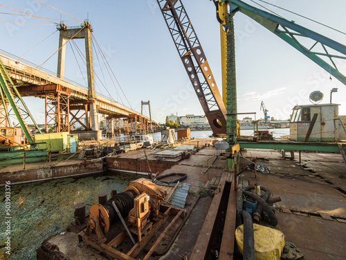 Kyiv, Ukraine – July 04, 2017: A big, old and rusty maritime crane. Building, reconstruction of a bridge. Industrial zone near a river.  photo
