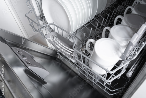 Stack of kitchenware in open dishwashing machine
