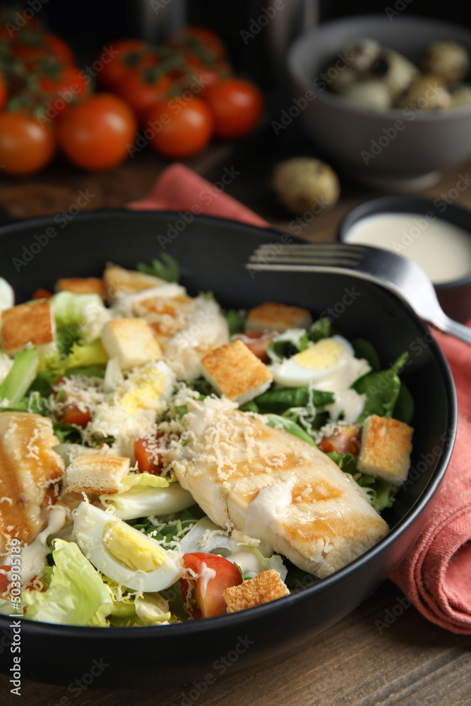 Delicious Caesar salad in bowl on wooden table, closeup
