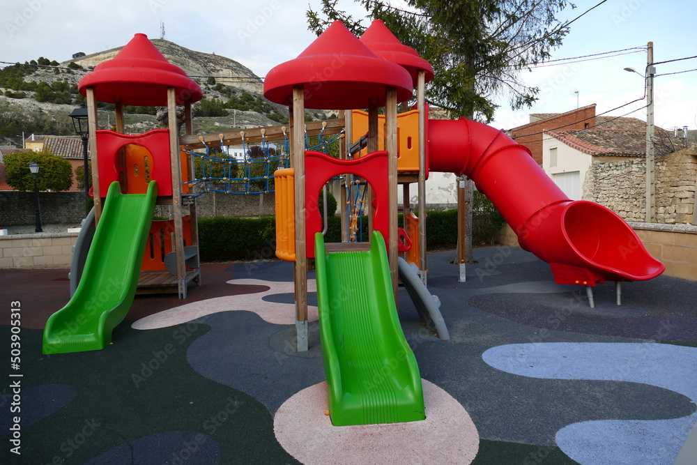 Parque infantil de columpios de colores rojo y verde. Toboganes y