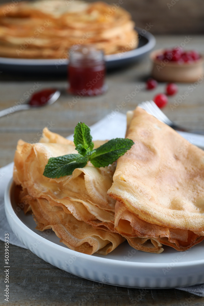 Delicious crepes served with mint on grey wooden table, closeup. Space for text