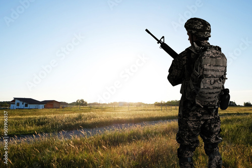 Soldier with machine gun outdoors, back view