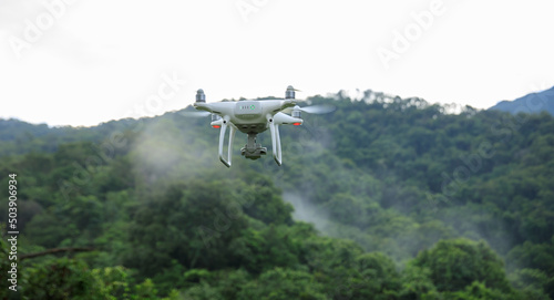 White drone with camera flying in summer forest